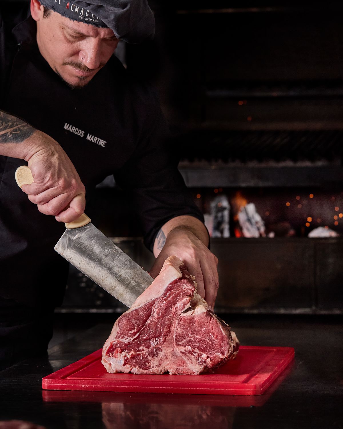 Marcos Martire, chef de Almacén de Carnes, cortando un bife junto al fuego
