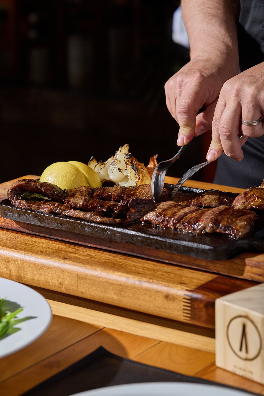Chef sirviendo entraña grillada con cebolla y limón