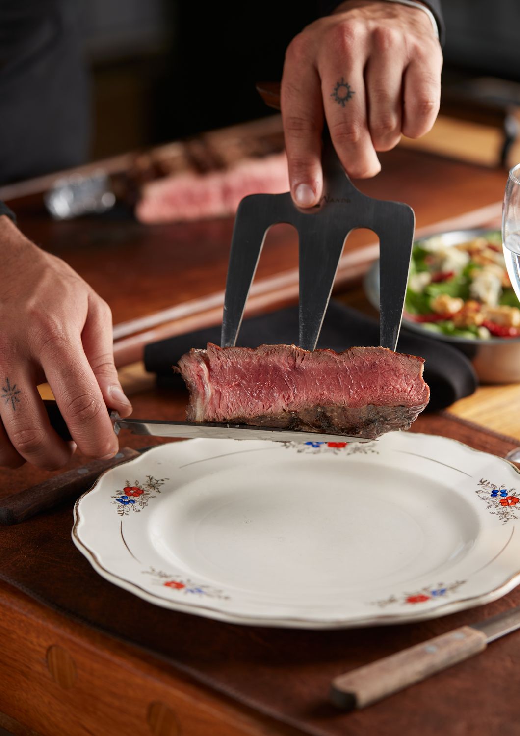 El chef cortando un bife jugoso, a punto, sobre el plato